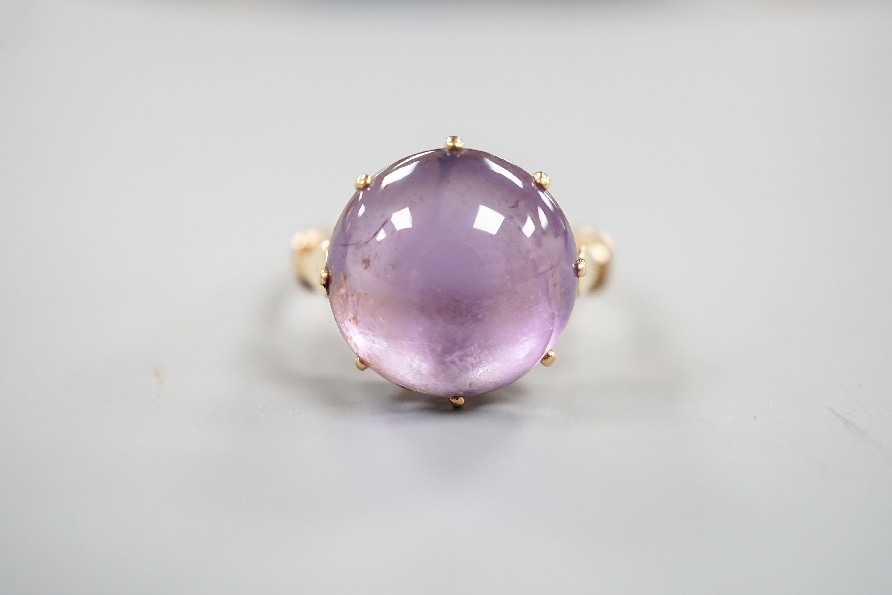 An early 20th century yellow metal and button shaped cabochon amethyst set ring, size R/S, gross weight 5.5 grams.